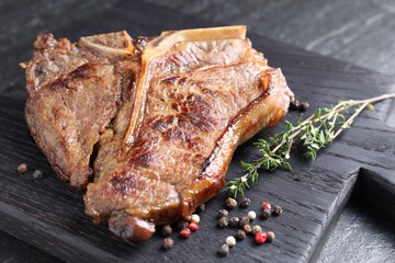Delicious fried beef meat, thyme and peppercorns on table, closeup