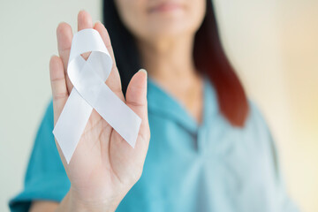 Asian female with white pearl ribbon awareness in hand for Dating Violence, Emphysema, Lung Cancer...