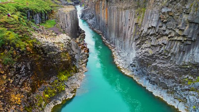 Flying through the Studlagil Canyon with the Jokulsa. Bru river in east Iceland, basalt rocks, Europe. Studlagil basalt rock columns canyon area and a stunning blue-green glacial river.