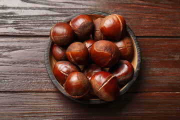 Roasted edible sweet chestnuts on wooden table, top view