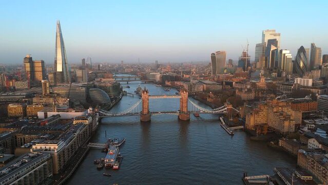 Amazing sunrise drone shot over London with a clear view of Tower Bridge, The Shard, and the city's skyline reflecting the early morning calm. The Gherkins. England, UK. Slow Motion, 4K RAW. 