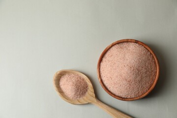 Himalayan salt in bowl and spoon on grey background, flat lay. Space for text