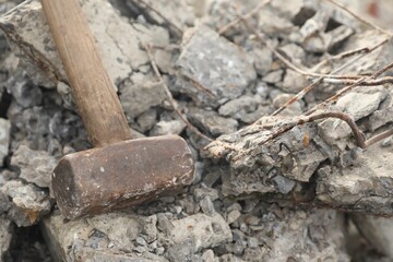 Fototapeta premium Sledgehammer on pile of broken stones outdoors, closeup
