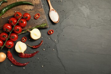 Cooking concept. Wooden cutting board and different products on black table, flat lay. Space for text