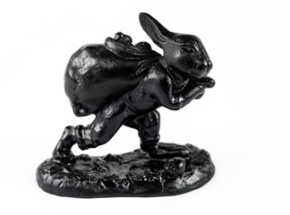 A purchased (consumer) figurine of a hare with a bag of cast iron in close-up on a white background