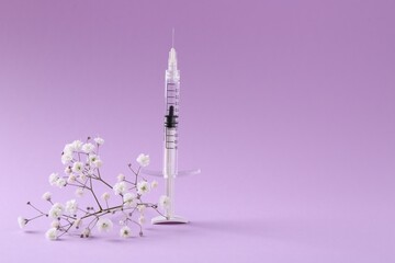 Cosmetology. Medical syringe and gypsophila on violet background, space for text