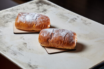 Homemade buns with jam with powdered sugar on wooden background. Fresh bakery on kitchen table. Sweet breakfast