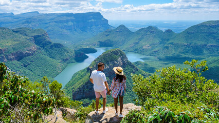 Panorama Route South Africa, Blyde river canyon with the three rondavels, Asian women and Caucasian men on vacation in South Africa looking out over green mountains on a road trip