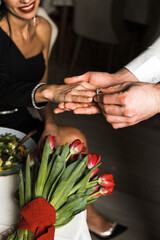 Obraz na płótnie Canvas Man proposing with an engagement ring to his love in a restaurant. closeup of a man putting an engagement ring on his girlfriend's hand. Marriage proposal concept