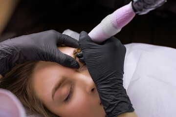 Using a tattoo machine, the master applies permanent makeup to the model's eyebrow. PMU Procedure, Permanent Eyebrow Makeup.