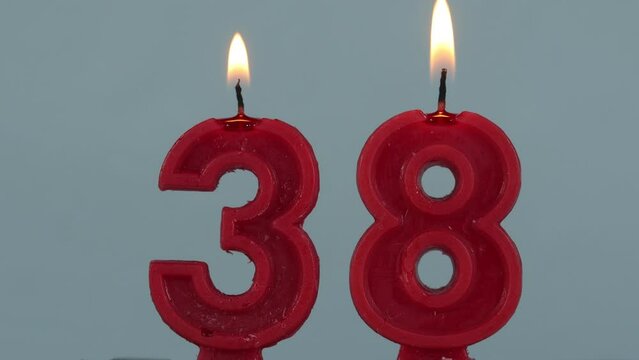 close up on timelapse melting a red number thirthy eighth birthday candle on a white background.
