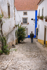 Fototapeta na wymiar Narrow small street of the old town with stone pavement, white walls of houses.
