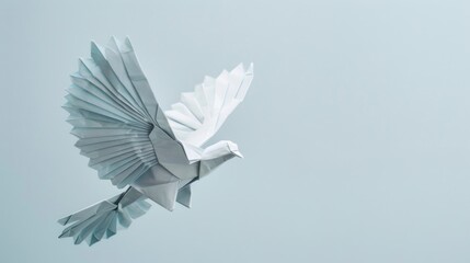 White origami bird in flight on a pale blue background.