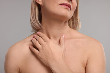 Woman touching her neck on grey background, closeup
