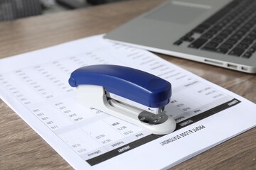 Bright stapler and document on wooden table