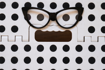 50's frame glasses on a plastic stool, forming an expression of terror.