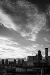 Black and white photo with spectacular clouds over the city of Barcelona (Spain), where several of the tallest buildings are outlined.