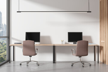 Office coworking interior with desk and pc monitors, panoramic window