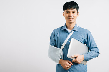 A resilient business professional, with a broken arm, utilizes a splint while working on a laptop....