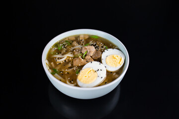ramen with meat in a white plate on a dark background