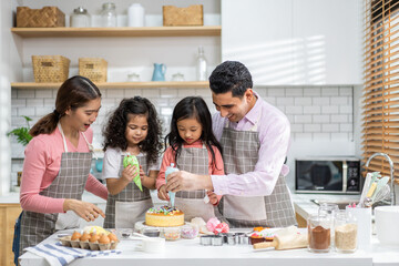 Portrait of enjoy happy love asian family father and mother with little asian girl daughter child play and having fun cooking food together with baking cookie and cake ingredient in kitchen