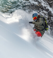Powder snowboarding. Freeride snowboarder girl riding off-trail fresh powder snow high in the mountains.
