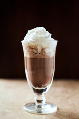 Coffee with whipped cream on dark wooden background. Close up.	