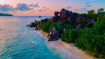 couple men and woman walking at the beach during sunset at a luxury vacation Seychelles