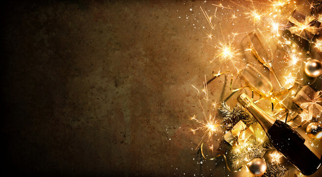 New Years Eve holiday background with fir branches, number 2022, champagne bottle, christmas balls, gift box and lights
