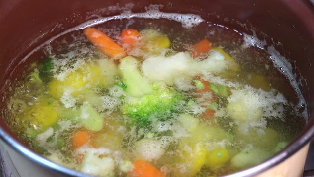 Boiling vegetarian soup with vegetables. Healthy diet food. Close up. Slow motion.