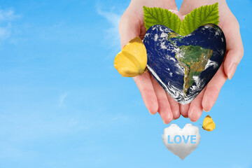 Earth heart shape in hands on blue sky background and Love to our world ,World environment and earth day concept.Elements of this image furnished by NASA.