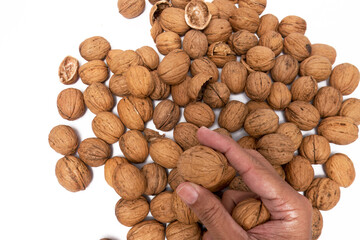 Hand Selecting Fresh, Organic Walnuts from a Pile, A close-up image capturing a hand selecting fresh, organic walnuts from a pile. The walnuts, in their shells, appear unprocessed and natural.