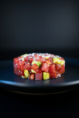 tar tar with tuna in a black plate on a dark background