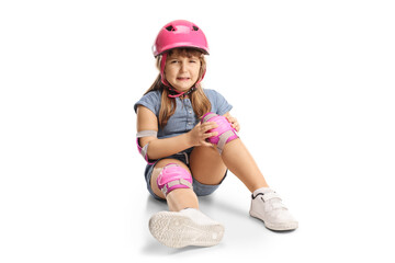 Child with a helmet and knee pads sitting on the floor and crying in pain