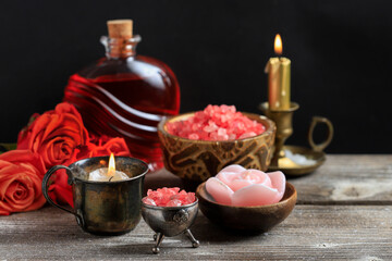 Read sea salt in wooden bowl, liquid soap and roses on the table.