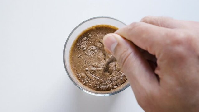 Above,male hand mixing with scoop of chocolate whey protein powder into a healthy shake for energy for training in a home kitchen. .Boy with nutritional sports supplement for musc.