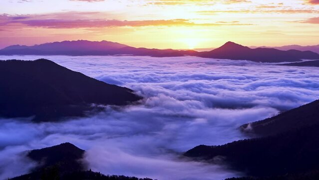 Misty mountains at sunrise: moving clouds and swirling fog create a tranquil and enchanting scene