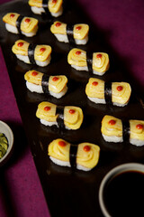 Tamago Nigiri served on a black wooden plate, avocado, cucumber, lump crab meat, sushi menu, social media post, food photography, fine dining, Japanese food, purple background