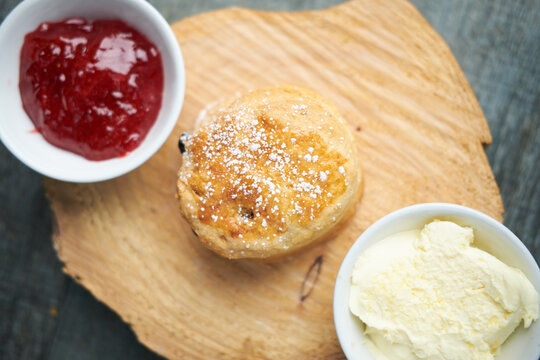 A beautiful gourmet scone served with tea and coffee, strawberry jam and clotted cream. traditional british food. Cackes and see treats