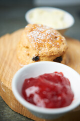 A beautiful gourmet scone served with tea and coffee, strawberry jam and clotted cream. traditional british food. Cackes and see treats