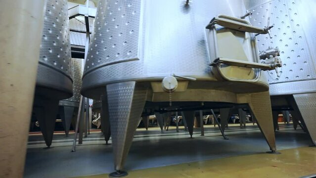 Modern winemaking factory with high stainless tanks for fermentation and distillation, process of high quality wine production in specialised facility, metal barrels for wine storage, viticulture