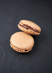 A collection of beautiful chocolate filled French macaroons sweet dessert, served on a rustic slate plate. Gourmet and posh trendy cafe and bakery treat. Sugar sweeties.