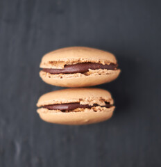 A collection of beautiful chocolate filled French macaroons sweet dessert, served on a rustic slate plate. Gourmet and posh trendy cafe and bakery treat. Sugar sweeties.