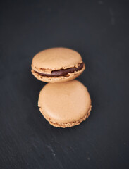 A collection of beautiful chocolate filled French macaroons sweet dessert, served on a rustic slate plate. Gourmet and posh trendy cafe and bakery treat. Sugar sweeties.