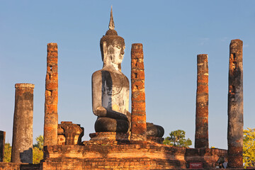 A giant stone Buddha statue at Sukhothai Historical Park at dusk, Thailand