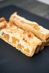 A beautiful delicious gourmet organic tomato and pumpkin quiche served on a rustic slate plate. Rustic fine dining lunch menu halloween fall season.
