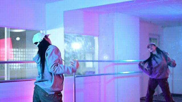 Active young woman enjoy practicing her dance moves in dace studio with neon lights