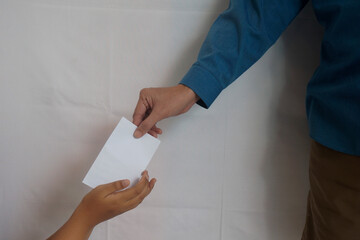 Muslim hand holding white envelope to give THR or pay Zakat Fitrah as an obligation in the holy...
