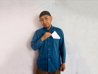Asian muslim man takes out the envelope full of money from his pocket to giving THR or Zakat Fitrah as an obligation in the holy month of Ramadan.