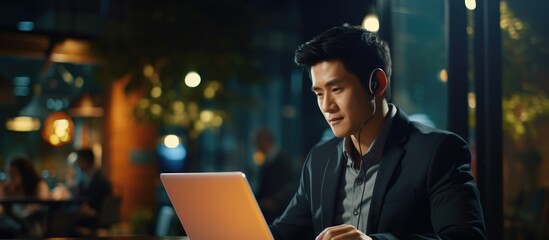Dedicated Asian businessman working late in office with his laptop, a customer service and call...